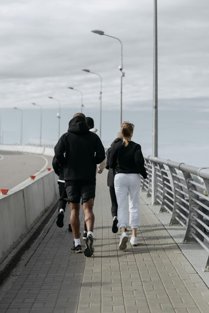 A group of joggers running on an urban sidewalk under overcast skies, embracing fitness together.